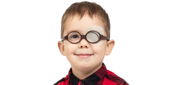 Image of a Young boy wearing glasses with an eye patch over one eye indicating treatment for amblyopia