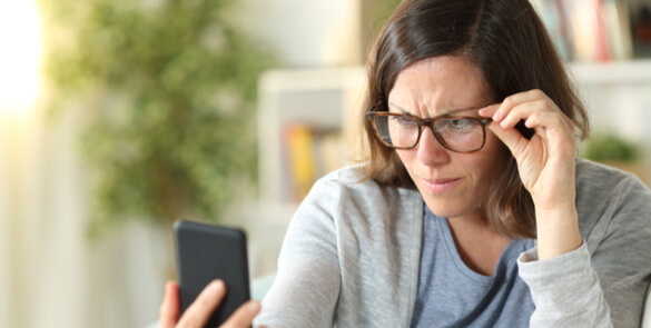 Middle-aged woman struggling to read a phone screen due to presbyopia, a common age-related eye condition treated at Moorfields Eye Hospital Dubai