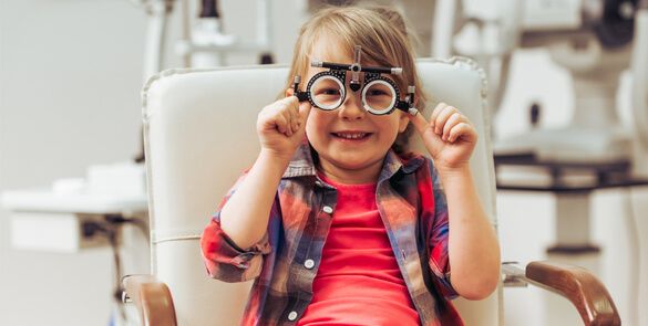 Smiling child wearing a trial lens frame during an eye exam ata Moorfields Eye Hospital Dubai