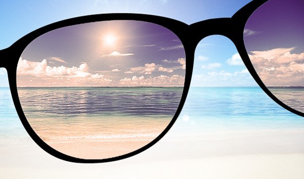 View of a sunny beach through sunglasses, illustrating summer eye care protection.