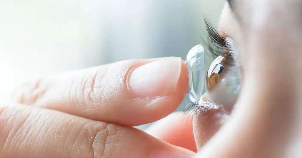 Close up image of a female applying Contact lens on her eye