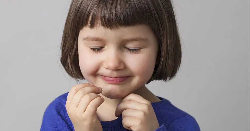 Young girl with closed eyes and slight smile, possibly demonstrating excessive blinking or an eye condition.