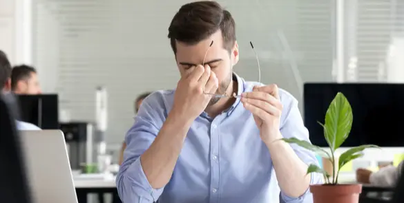 Man experiencing eye strain or fatigue from prolonged screen time, a common concern in digital eye health.
